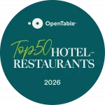 Auf einem runden Abzeichen in dunklem Blaugrün steht in weißer und grüner Schrift „OpenTable Top 50 Hotel-Restaurants 2026“.