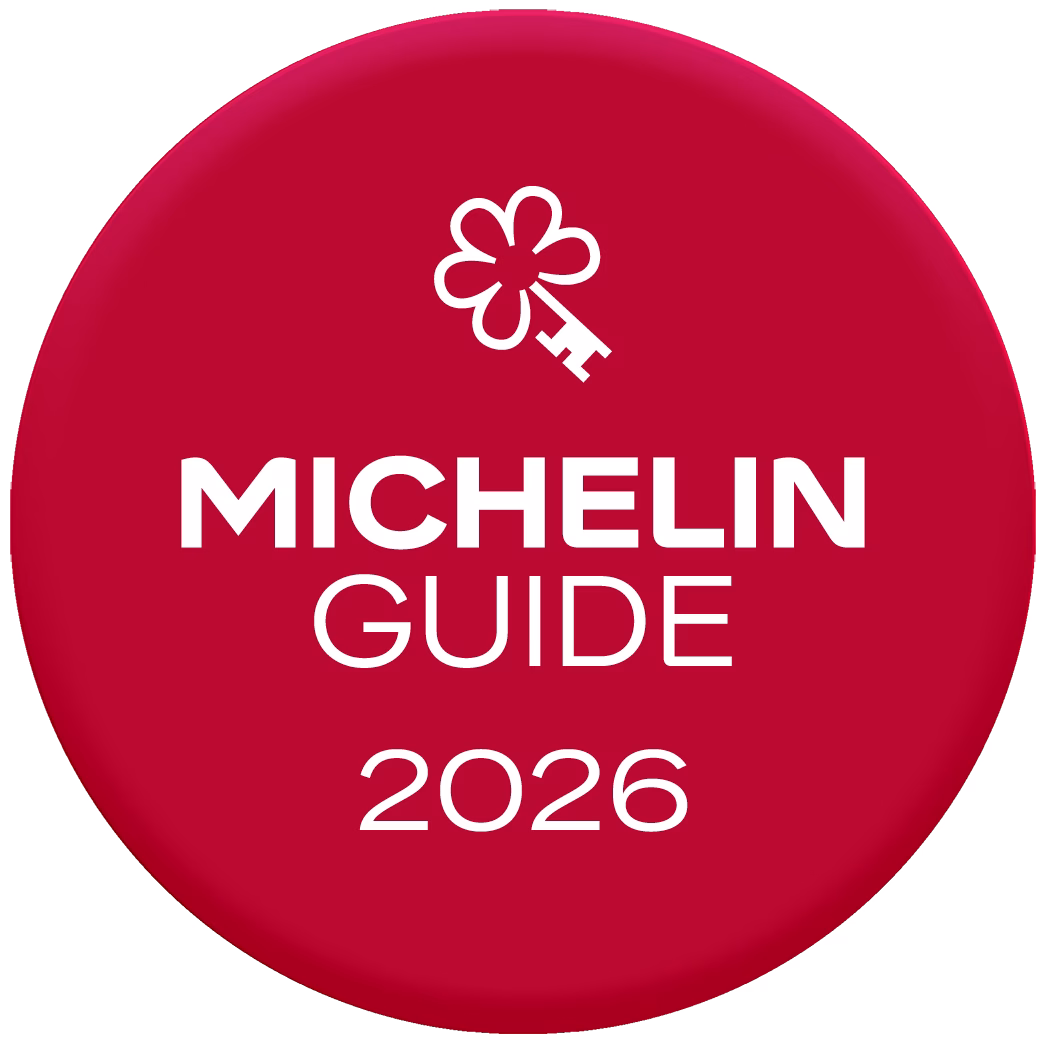 Logo des Michelin-Führers 2026 mit einem stilisierten, blumenförmigen Schlüssel auf rotem, rundem Hintergrund. Logo des Michelin-Führers 2026 mit einem stilisierten, blumenförmigen Schlüssel auf rotem, rundem Hintergrund.